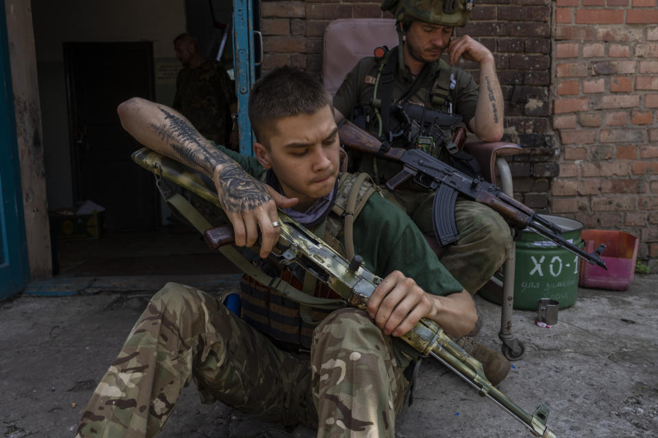 A security member of a medical rescue team cleans his weapon in the Donetsk oblast region, eastern Ukraine, Saturday, June 4, 2022. (AP Photo/Bernat Armangue)