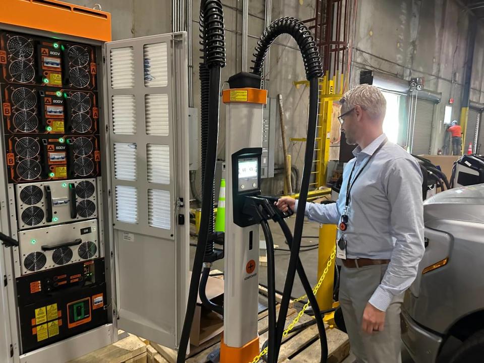 Marcus Suvanto of Kempower places a nozzle back in one of its EV charger satellites at the company’s new plant in Durham. The system’s power unit, left, can be placed up to 260 feet away from the satellites.
