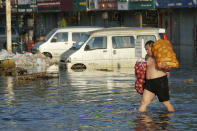 A man carries bags of onions out of the flooded Yubei Agricultural and Aquatic Products World in Xinxiang in central China's Henan Province, Monday, July 26, 2021. Record rain in Xinxiang last week left the produce and seafood market soaked in water. Dozens of people died in the floods that immersed large swaths of central China's Henan province in water. (AP Photo/Dake Kang)