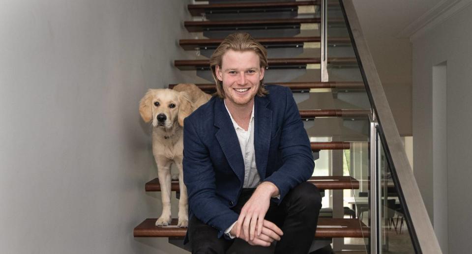 eCommerce businessman Davie Fogarty sitting on a staircase with his dog
