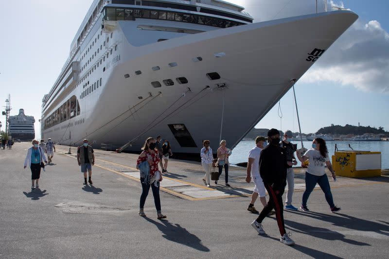 Passengers of the Costa Luminosa cruise ship wearing protective face masks make their way at the port of the island of Corfu