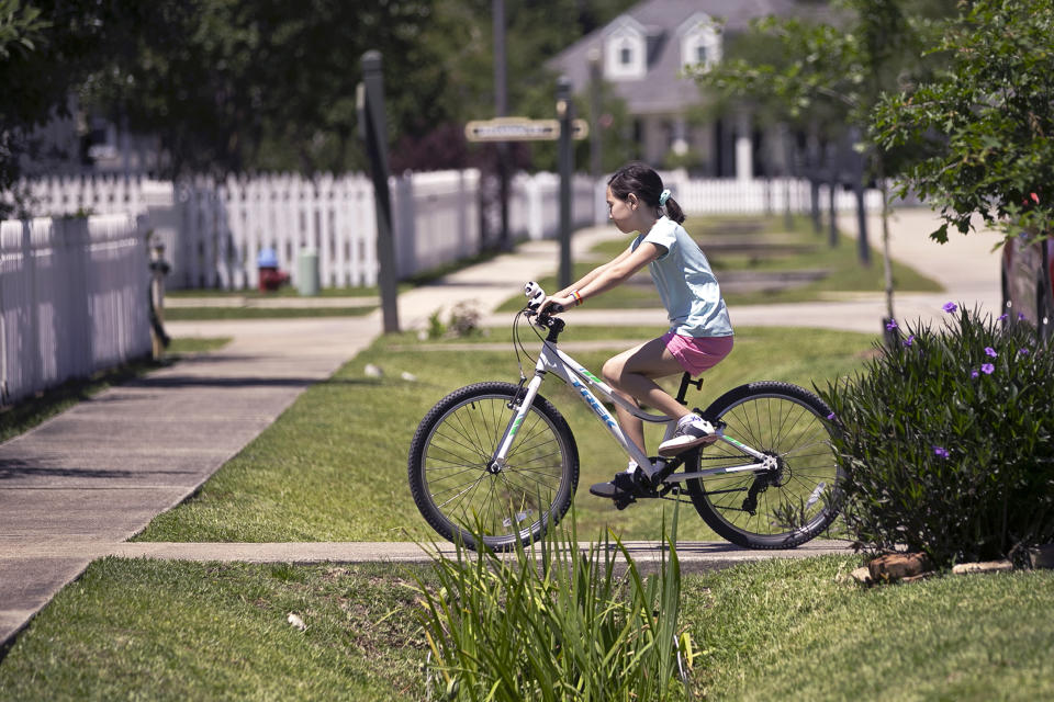 Juliet Daly, 12, rides her bike outside her home in Covington, La., Thursday, April 30, 2020. A team of pediatric cardiology specialists found that Juliet had acute fulminant myocarditis (AFM), an uncommon heart condition that tends to present with sudden onset acute heart failure, cardiogenic shock or life-threatening arrhythmias. A nasal swab confirmed that Juliet was also COVID-19 positive and that she had a second viral infection – adenovirus. (AP Photo/Gerald Herbert)