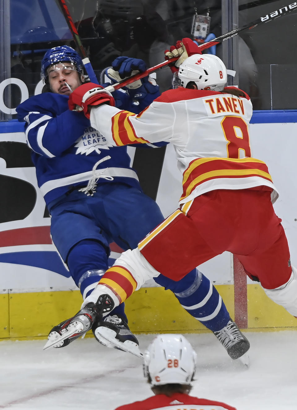 Calgary Flames defenseman Christopher Tanev (8) hits Toronto Maple Leafs forward Auston Matthews (34) during first-period NHL hockey game action in Toronto, Saturday, March 20, 2021. (Nathan Denette/The Canadian Press via AP)