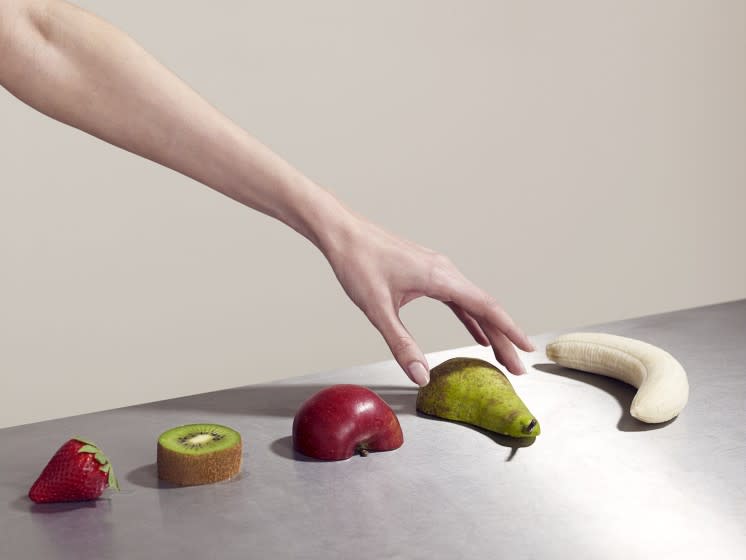 Woman picking up piece of fruit