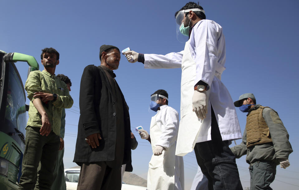 FILE - In this Sunday, March 22, 2020 file photo, health workers measure the temperature of Afghan passengers in an effort to prevent the spread of the coronavirus, as they enter Kabul trough Kabul's western entrance gate, in the Paghman district of Kabul, Afghanistan. An international aid group says Friday, May 22, 2020 that some 661,000 people in 19 countries have been displaced by armed conflict in the two months since the U.N. secretary general called for a global cease-fire to help curb the coronavirus pandemic. The Norwegian Refugee Council says in a report Friday that the bulk of the newly displaced were in the Democratic Republic of Congo, but that large numbers were also uprooted in Yemen, Afghanistan, Chad and Niger. (AP Photo/Rahmat Gul, File)