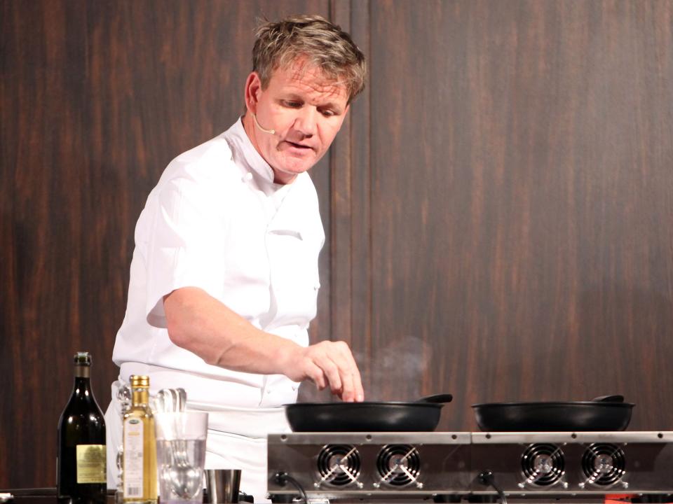 Gordon Ramsay cooking at a stove with heated pans.