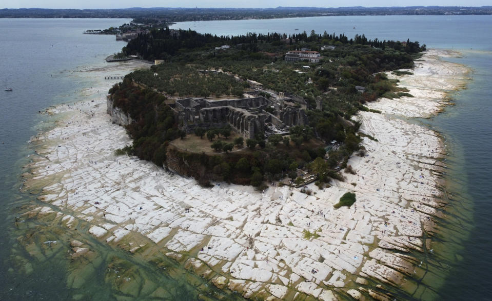 A view of the peninsula of Sirmione, on Garda lake, Italy, Friday, Aug. 12, 2022. Lake Garda water level has dropped critically following severe drought resulting in rocks to emerge around the Sirmione Peninsula. (AP Photo/Antonio Calanni)