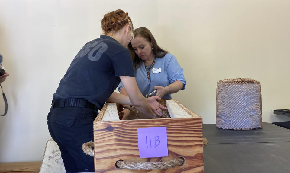 Forensic anthropologist Madeline Atwell, foreground, and Stacey Ferguson of the Historic Camden Foundation, background, prepare the remains of an unidentified Revolutionary War soldier killed in the Battle of Camden in 1780 for reburial on Thursday, March 30, 2023, in Columbia, South Carolina. The remains of 14 soldiers were removed from the battlefield, studied and analyzed and will be buried in a ceremony. (AP Photo/Jeffrey Collins)