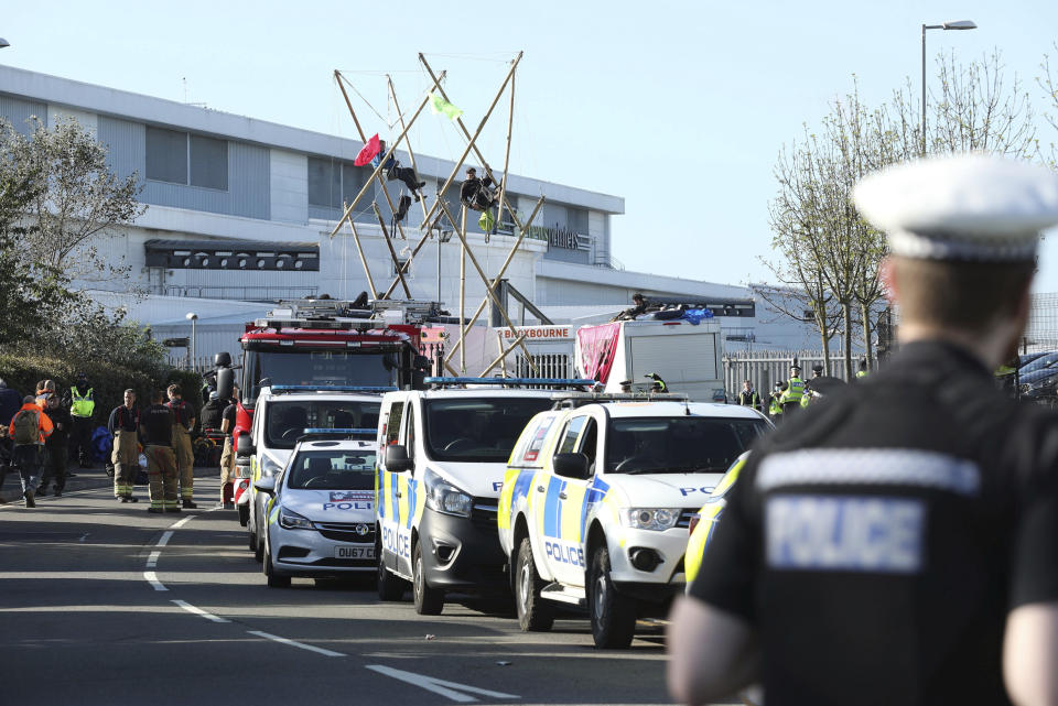 Police and fire services at the scene, outside Broxbourne newsprinters as protesters continue to block the road, in Broxbourne, Hertfordshire, England, Saturday, Sept. 5, 2020. Environmental activists have blockaded two British printing plants, disrupting the distribution of several national newspapers. The group Extinction Rebellion said it targeted printworks at Broxbourne, north of London, and Knowsley in northwest England that are owned by Rupert Murdoch’s News Corp. Dozens of protesters locked themselves to vehicles and bamboo scaffolding to block the road outside the plants. The facilities print Murdoch-owned papers The Sun and The Times, as well as the Daily Telegraph, the Daily Mail and the Financial Times. (Yui Mok/PA via AP)