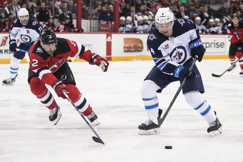 New Jersey Devils' Brendan Smith (2) defends against Winnipeg Jets' Neal Pionk (4) during the third period of an NHL hockey game Sunday, Feb. 19, 2023, in Newark, N.J. The Devils won 4-2. (AP Photo/Frank Franklin II)