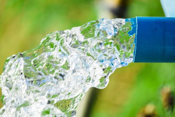 Water gushing out of a blue pipe.