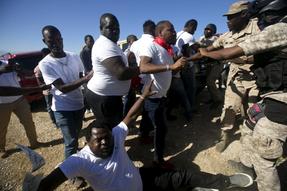 National police officers push anti government protesters who tries to place flowers at Titanyen, a mass burial site, as Haiti's President Jovenel Moise attends a memorial service honoring the victims of the 2010 earthquake in Port-au-Prince, Haiti,Sunday, Jan. 12, 2020. Sunday marks the 10th anniversary of the devastating 7.0 magnitude earthquake that destroyed an estimated 100,000 homes across the capital and southern Haiti, including some of the country's most iconic structures. (AP Photo/Dieu Nalio Chery)