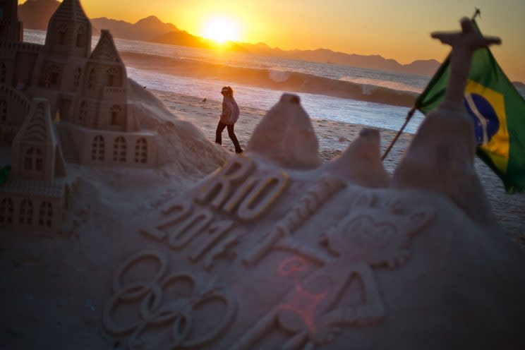 A jogger runs along Copacabana beach as a sand sculpture stands along the promenade Monday, Aug. 1, 2016, in Rio de Janeiro, Brazil. The iconic Copacabana beach will be the starting point for the road cycling race, marathon swimming and triathlon competitions during the Olympics. (AP Photo/David Goldman)