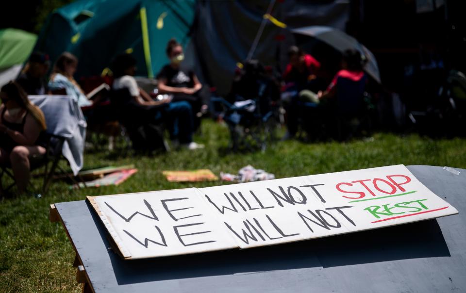 A hand made sign sits in front of demonstrators as they gather and talk in Dunn Meadow on May 10, 2024.