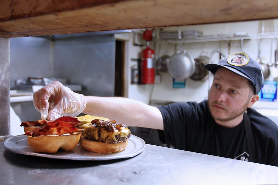 Jimmie Rogers, a cook with Choice City, puts the final touches on a burger during Choice City's 2-for-1 burger night Feb. 8 in Fort Collins. Choice City, which almost closed earlier this year, celebrated 20 years in business in Old Town this month.