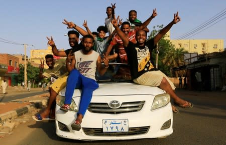 Sudanese people ride atop a car chanting slogans as they celebrate, after Sudan's ruling military council and a coalition of opposition and protest groups reached an agreement to share power during a transition period leading to elections, in Khartoum