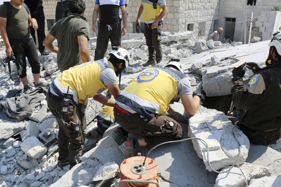 This photo provided by the Syrian Civil Defense White Helmets, which has been authenticated based on its contents and other AP reporting, shows Syrian White Helmet civil defense workers search for victims from under the rubble of a destroyed building that hit by airstrikes, in Deir al-Sharqi village, in Idlib province, Syria, Saturday, Aug 17, 2019. Syrian activists and a war monitor say airstrikes have pounded the southern edge of a rebel stronghold in the country's northwest, in one instance killing seven including children. (Syrian Civil Defense White Helmets via AP)