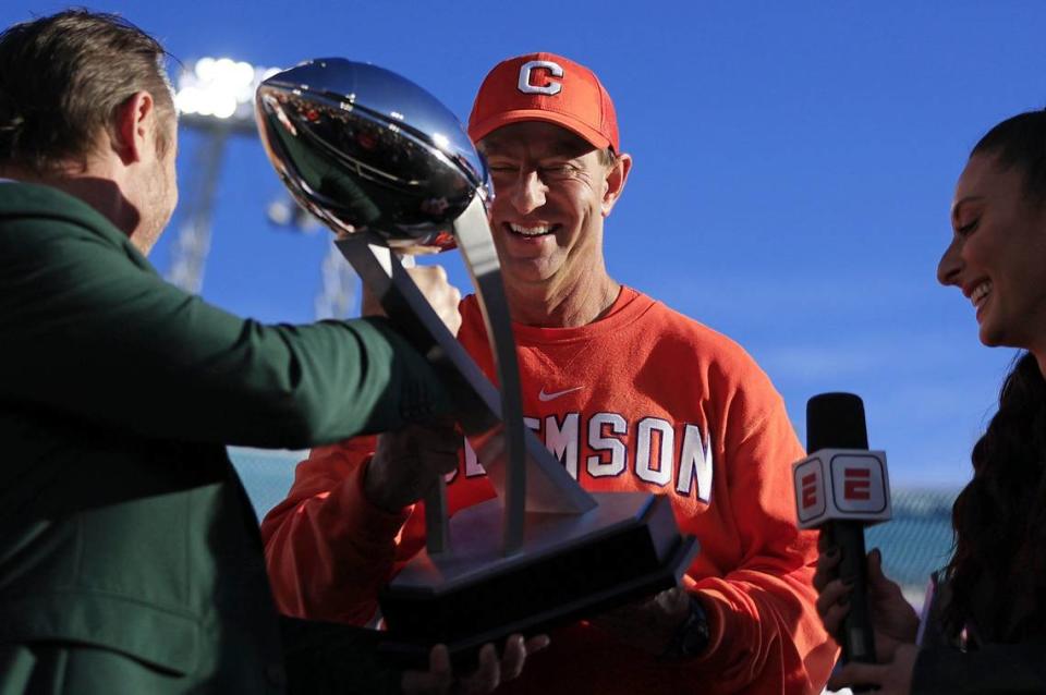 Clemson Tigers head coach Dabo Swinney admires the Ash Verlander Champions Trophy before hoisting it over his head after the game of an NCAA football matchup in the TaxSlayer Gator Bowl Friday, Dec. 29, 2023 at EverBank Stadium in Jacksonville, Fla. The Clemson Tigers edged the Kentucky Wildcats 38-35.