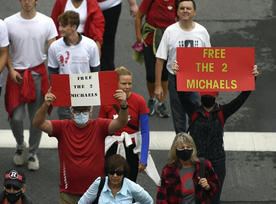 People hold signs in Ottawa calling for the release of the two Michaels.