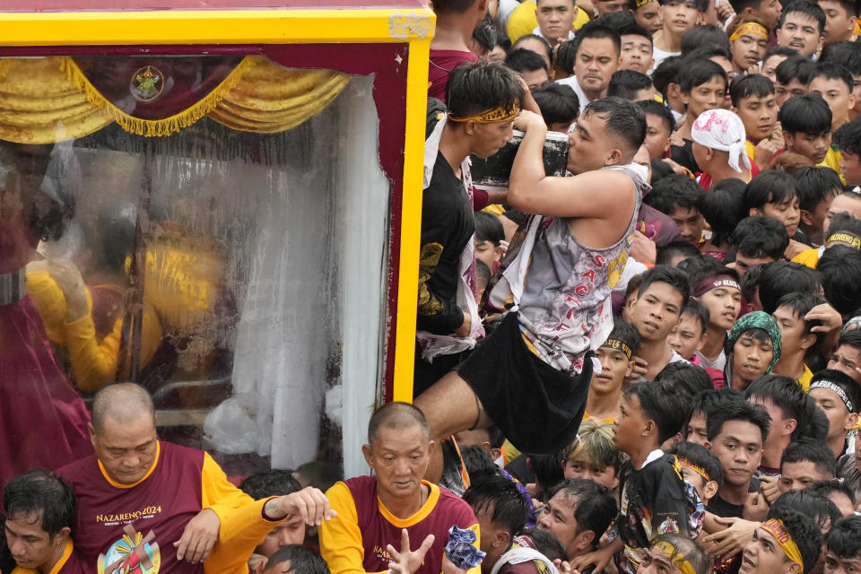 A devotee kisses the crucifix of the Black Nazarene during its annual procession which was resumed after a three-year suspension due to the coronavirus pandemic on Tuesday, Jan. 9, 2024 in Manila, Philippines. A mammoth crowd of mostly barefoot Catholic devotees joined a chaotic procession through downtown Manila Tuesday to venerate a centuries-old black statue of Jesus Christ with many praying for peace in the Middle East where Filipino relatives work. (AP Photo/Aaron Favila)