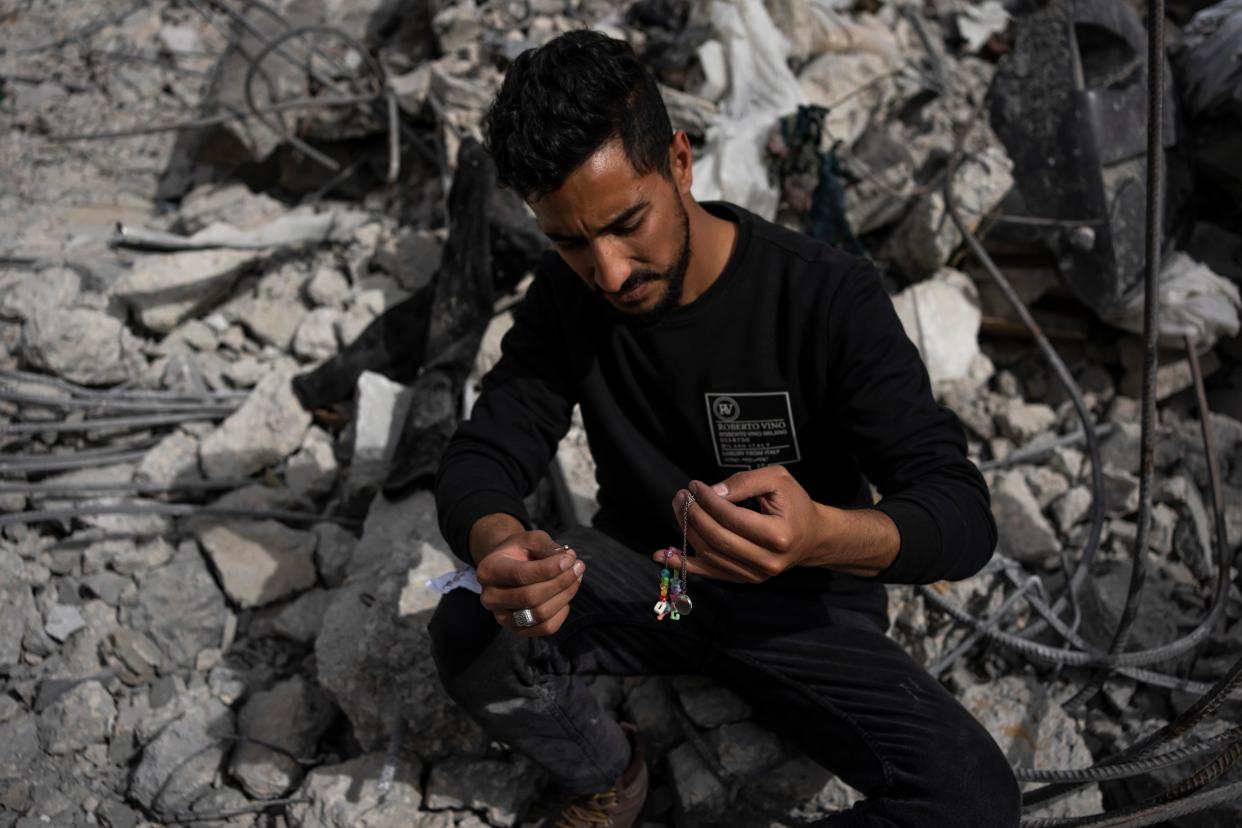 Ibrahim Hasouna, center, the sole survivor among his family, sits amidst the debris of his bombed home in Rafa (AP)