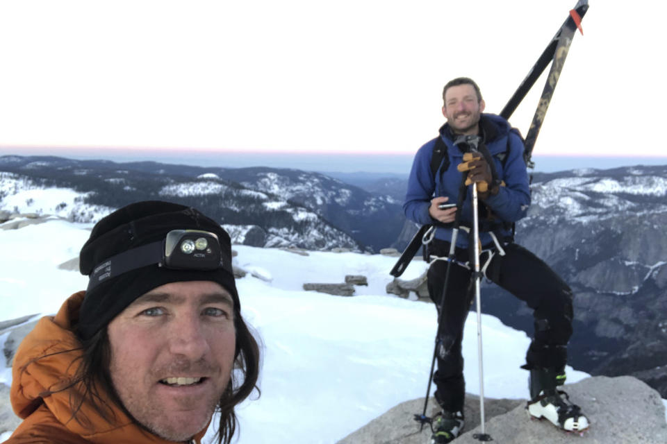 In this photo provided by Jason Torlano, he poses with his friend, Zach Milligan, right, on Half Dome in Yosemite National Park, Calif., on Sunday, Feb. 21, 2021. Two men climbed some 4,000 feet to the top of Yosemite's Half Dome in subfreezing temperatures and skied down the famously steep monolith to the valley floor. Torlano, 45, and Milligan, 40, completed the daring descent in five hours on Sunday by charging down Half Dome's arching back and using ropes to rappel down several sections of bare rock known as the "death slabs," the Fresno Bee reported on Thursday. (Jason Torlano via AP)