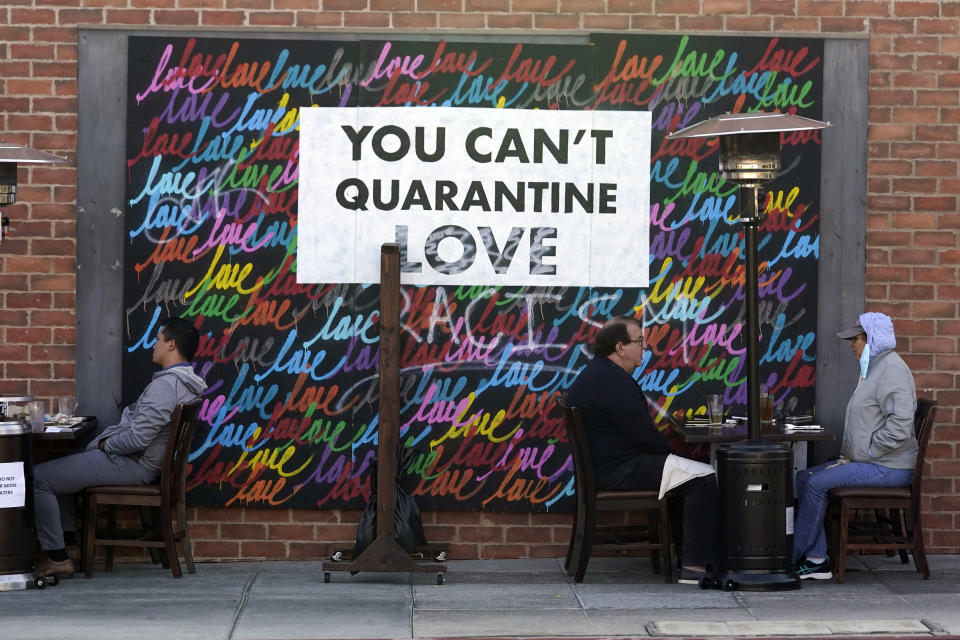 A COVID-19-themed mural reads "You Can't Quarantine Love," outside of a restaurant, Monday, Nov. 23, 2020, in Santa Monica, Calif. (AP Photo/Marcio Jose Sanchez)