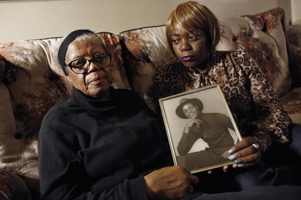 FILE- In this March 12, 2014 file photo, Alma Murdough and her daughter Cheryl Warner hold a photo of Murdough's son, at her home in the Queens borough of New York. Jerome Murdough, a mentally ill, homeless former Marine arrested for sleeping in the roof landing of a New York City public housing project during one of the coldest recorded winters in city history, died in a Rikers Island jail cell that multiple city officials say was at least 100 degrees when his body was discovered. The former Marine will be buried in New Jersey on Friday, April 25, 2014, after a modest funeral service in the Queens borough of New York. (AP Photo/Jason DeCrow, File)