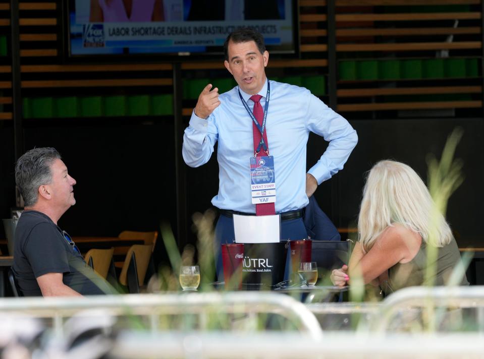 Former Wisconsin Gov. Scott Walker Members, who leads the Young America's Foundation, co-hosting the debate, talks to people at the Mecca Sports Bar across from Fiserv Forum as work is done Tuesday in preparation for the Aug. 23 Republican presidential debate in Milwaukee.