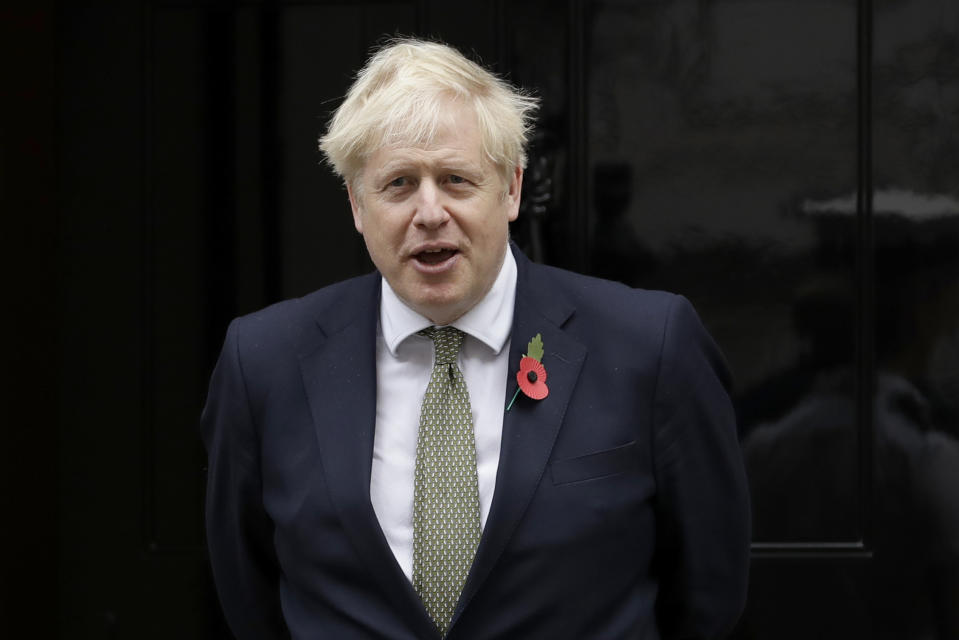 British Prime Minister Boris Johnson poses for photographs with members of the British military to mark the launch of the annual Royal British Legion Poppy appeal outside 10 Downing Street, in London, Friday, Oct. 23, 2020. (AP Photo/Matt Dunham)