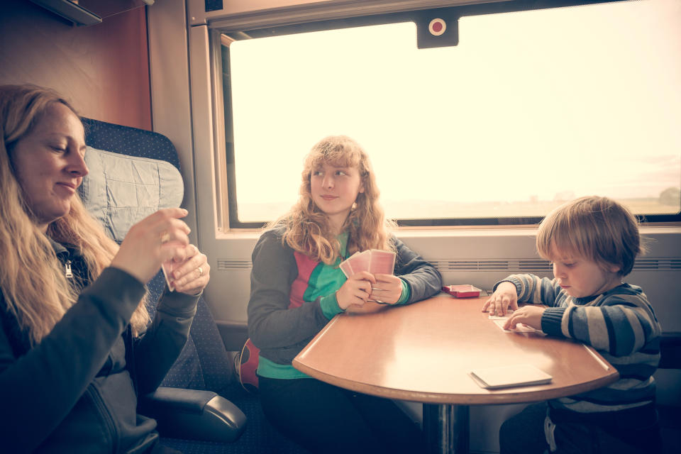 Mother, teen daughter and toddler son playing with cards during a train journey