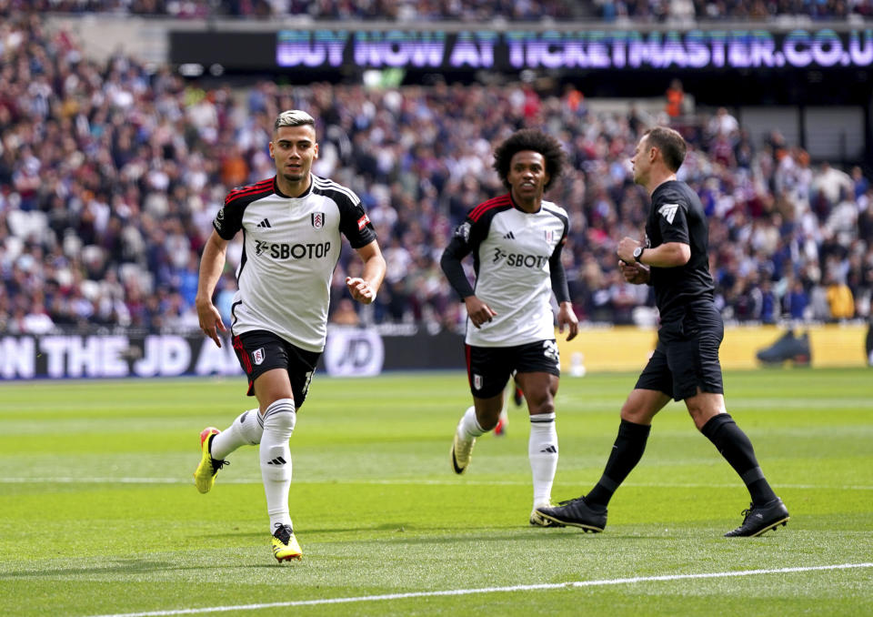 Fulham's Andreas Pereira, left, celebrates scoring his side's first goal of the game during the English Premier League soccer match between West Ham United and Fulham, at the London Stadium, London, Sunday April 14, 2024. (Bradley Collyer/PA via AP)