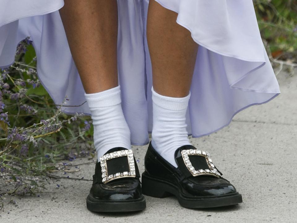 person wearing flowy purple dress with black loafers with big silver buckles