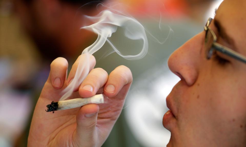 A man smokes a marijuana joint in a public space during a party celebrating weed on April 20, 2016.