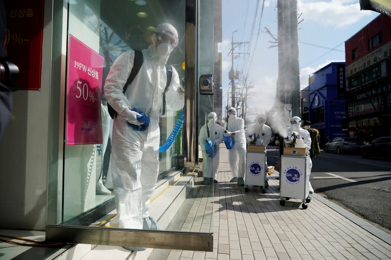 Employees from a disinfection service company sanitize a shopping district in Seoul