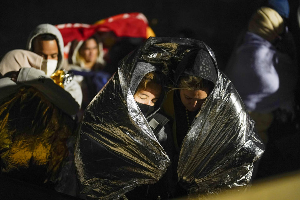 FILE - Two women from Cuba try to keep warm after crossing the border from Mexico and surrendering to authorities to apply for asylum on Thursday, Nov. 3, 2022, near Yuma, Arizona. An underground market has emerged for migrants seeking U.S. sponsors since the Biden administration announced last month that it would accept a limited number of people from Venezuela, Cuba, Nicaragua and Haiti. Applicants for the humanitarian parole program need someone in the U.S. to promise to provide financial support for at least two years. (AP Photo/Gregory Bull)