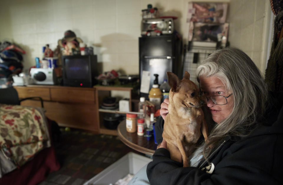 In this Oct. 11, 2018, photo, Melissa Smith holds her dog Bella in her room at a weekly rental motel in Reno, Nev. Smith has lived in weekly and monthly rental motels for about two years. (AP Photo/John Locher)