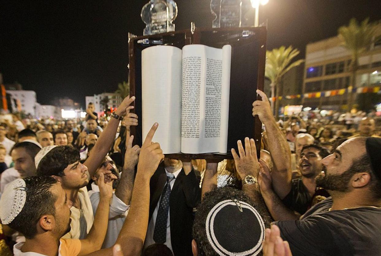 Simchat Torah celebrations in Netanya, Israel, in 2013. <a href="https://www.gettyimages.com/detail/news-photo/jews-dance-as-they-read-from-a-torah-scroll-during-the-news-photo/181935434?phrase=simchat%20torah&adppopup=true" rel="nofollow noopener" target="_blank" data-ylk="slk:Jack Guez/AFP via Getty Images;elm:context_link;itc:0;sec:content-canvas" class="link ">Jack Guez/AFP via Getty Images</a>