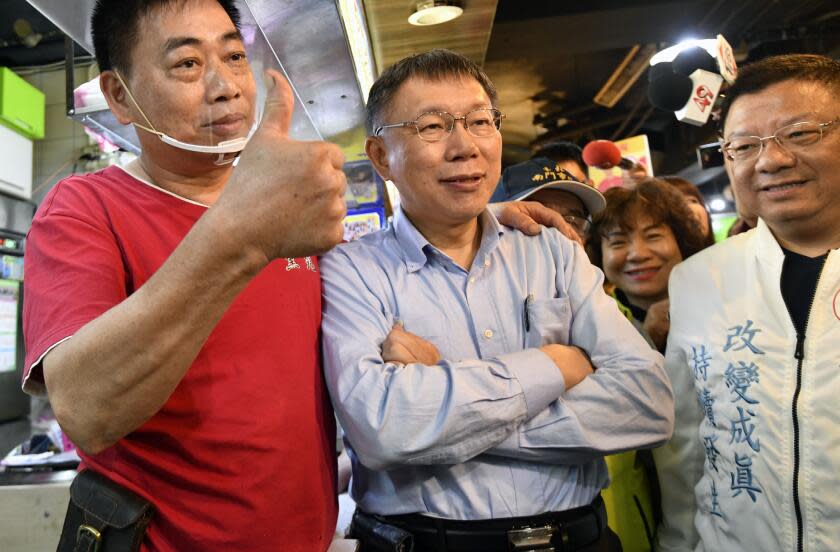 This picture taken on November 9, 2018 shows independent Taipei mayor candidate Ko Wen-je (C) posing for photos with a supporter (L) during the elections campaign at a traditional market in Taipei. - When Taiwan goes to the polls on November 24, 2018 in local elections, it will not only be a test for President Tsai Ing-wen's embattled government but a crucial vote on divisive issues that could rile China. (Photo by SAM YEH / AFP) / TO GO WITH STORY: Taiwan-China-vote-referendum-politics, ADVANCER by Amber WANG (Photo credit should read SAM YEH/AFP via Getty Images)