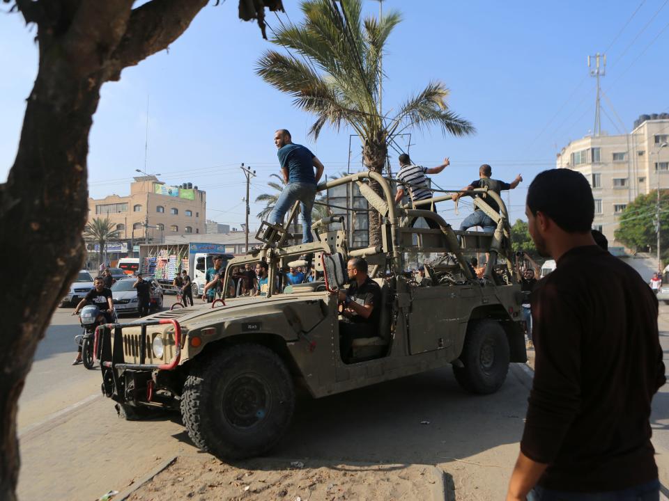 Palestinians ride on an Israeli military vehicle taken by an army base overrun by Hamas militants near the Gaza Strip fence on October 7, 2023.