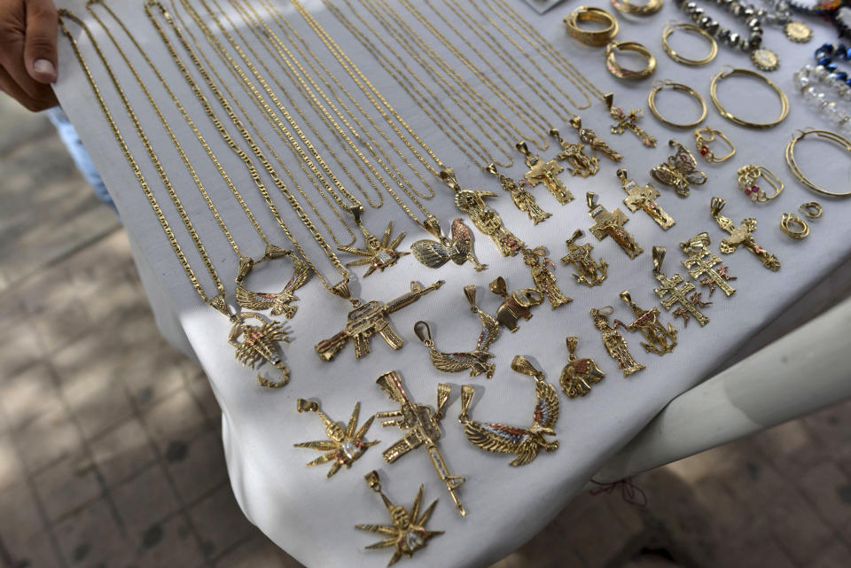 FILE - In this July 22, 2015 file photo, a man sells jewelry, many of it with narco-culture imagery, in downtown Culiacan, Mexico. U.S. officials hailed the conviction of Joaquin “El Chapo” Guzman as a victory for the Mexican people, but in the drug lord’s home state of Sinaloa, cradle to his powerful cartel, many residents said they don’t expect the violence and trafficking to abate. (AP Photo/Fernando Brito, File)
