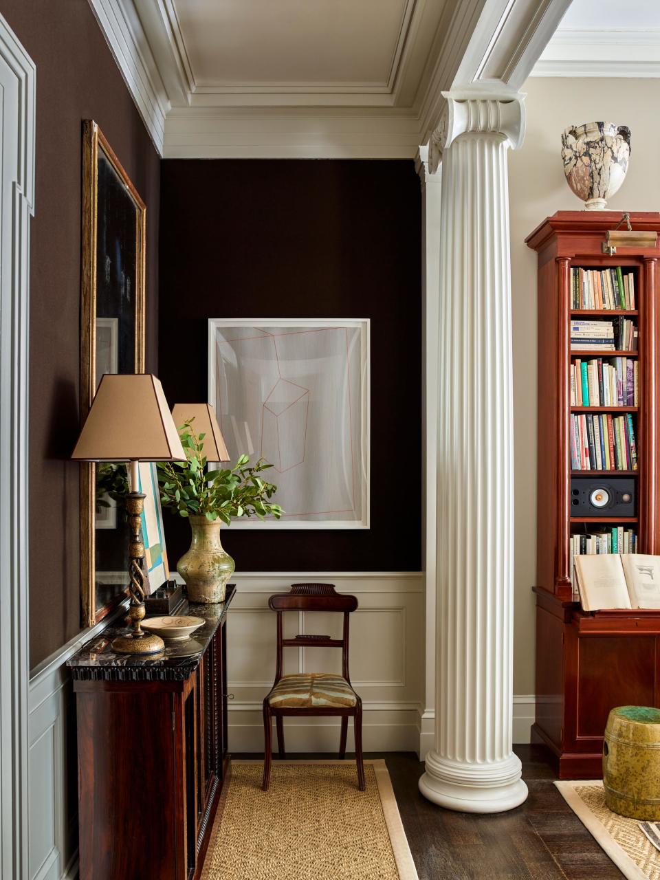 A nook off the living room features a Regency mahogany cabinet from Niall Smith Antiques, a mahogany side chair from Sutter Antiques, and original artwork by Maine artist Corey Daniels. The Kashmiri lamps are from Robert Kime, and the marble urn was acquired at an auction at Christie’s.