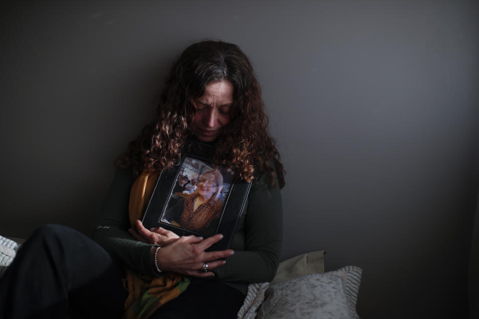 Fernanda Mariotti cradles a picture of her mother Martha Pedrotti, who passed away a victim of COVID-19, at her home in Buenos Aires, Argentina, Tuesday, Aug. 11, 2020. Mariotti believes that her mother eventually died in part from a heart condition and also from the sorrow and fear of being separated from her family, isolated in the COVID unit. (AP Photo/Natacha Pisarenko)