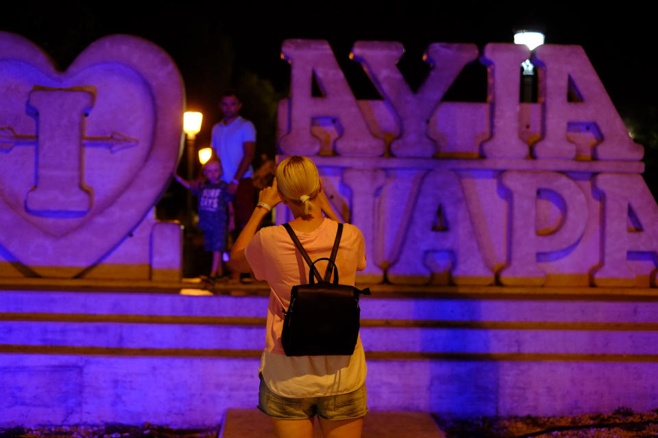 Tourist pose for photo at a sculpture that read "I Love Ayia Napa" in the southeast resort of Ayia Napa in the easter Mediterranean island of Cyprus late Wednesday, July 17, 2019. A Cyprus police official says 12 Israelis have been detained after a 19-year-old British woman alleged that she was raped in the resort town of Ayia Napa. (AP Photo/Petros Karadjias)