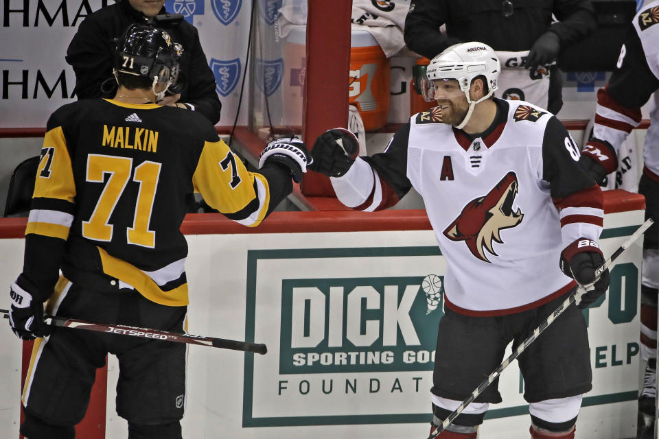 Two-time Stanley Cup Champion with the Pittsburgh Penguins, Arizona Coyotes' Phil Kessel, right, is welcomed back by former linemate Pittsburgh Penguins' Evgeni Malkin (71) following a tribute to him during a timeout in the first period of an NHL hockey game in Pittsburgh, Friday, Dec. 6, 2019. (AP Photo/Gene J. Puskar)