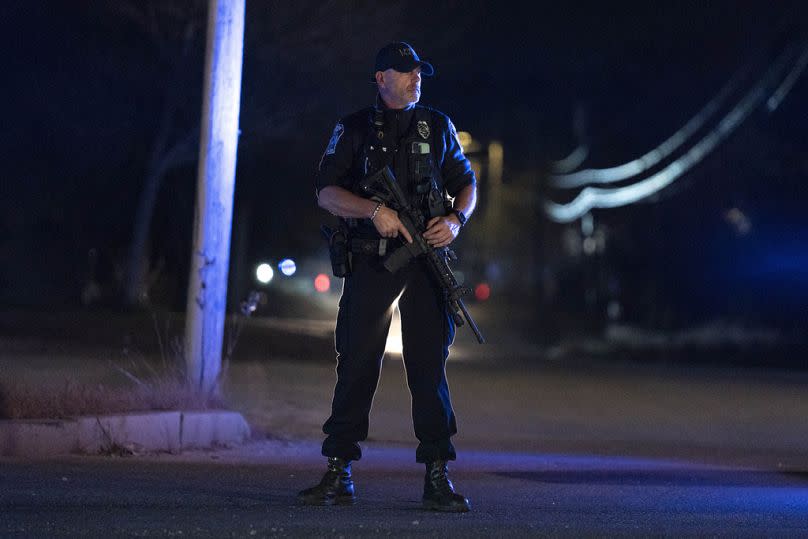 A police officer guards the road to a recycling facility where the body of Robert Card was found, Friday, Oct. 27, 2023, in Lisbon, Maine.