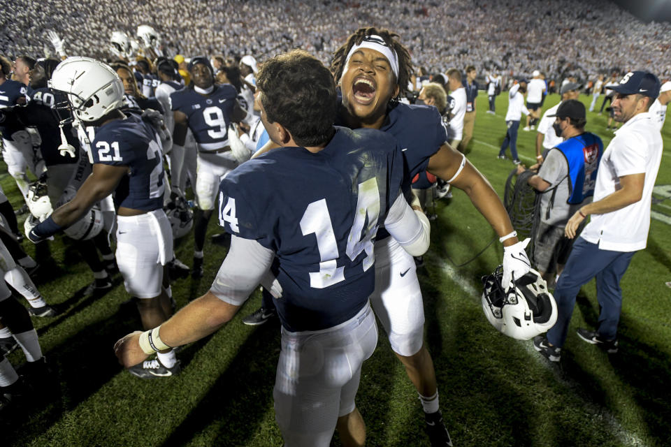 Penn State quarterback Sean Clifford (14) and defensive end Davon Townley (18) celebrate the 28-20 victory over Auburn in an NCAA college football game in State College, Pa., on Saturday, Sept. 18, 2021. (AP Photo/Barry Reeger)