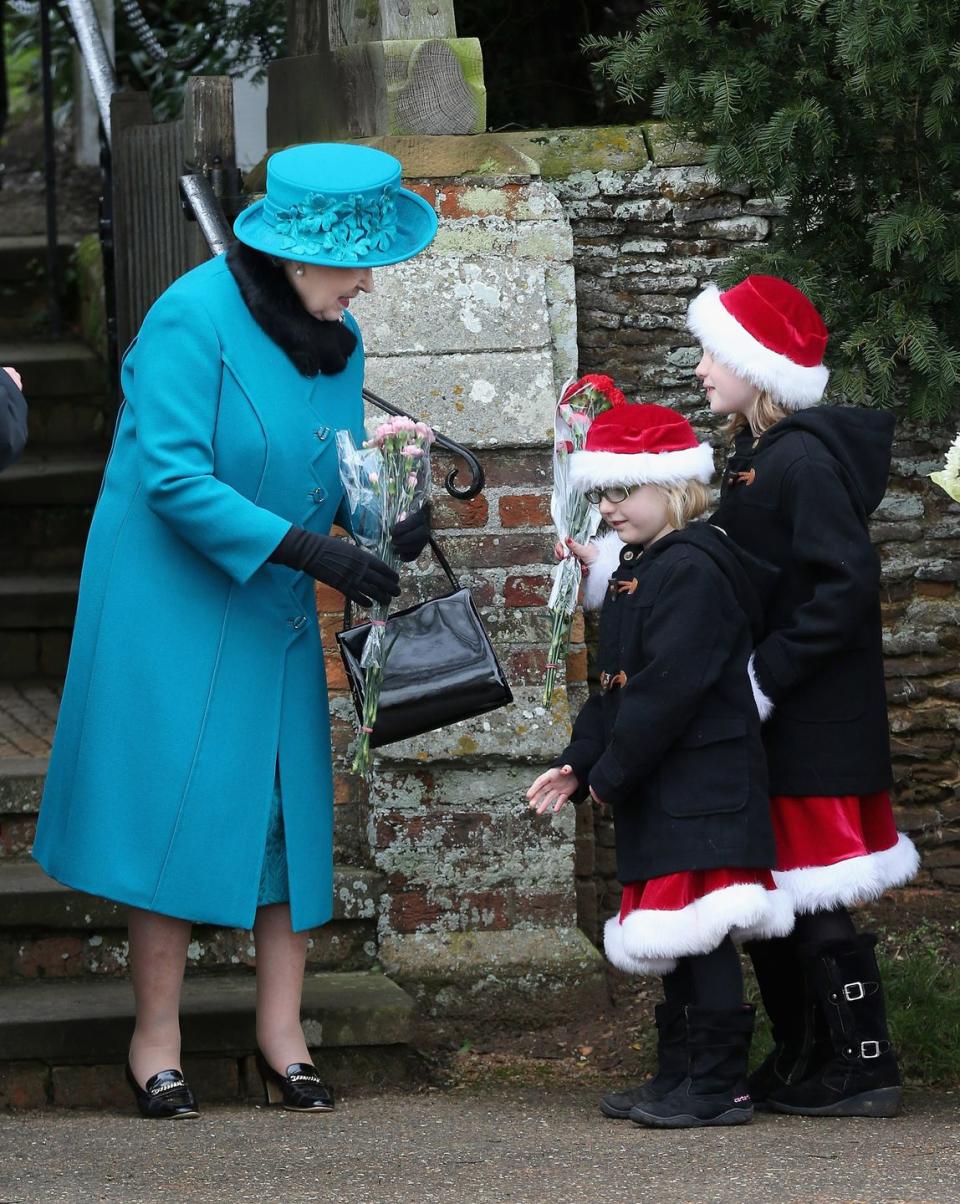 <p>While leaving Christmas service at St Mary Magdalene Church in Sandringham, the Queen is gifted flowers by two young girls in Santa costumes. </p>