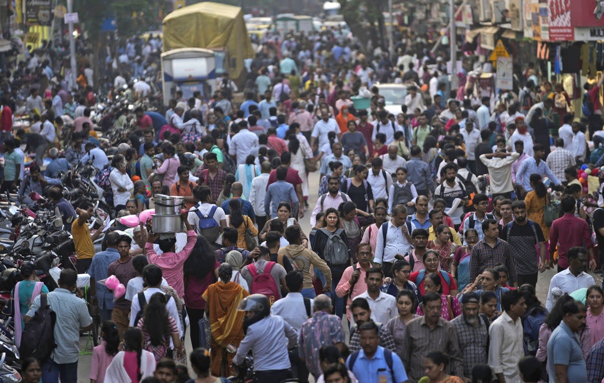 A crowd walks in a market area outside Dadar station in Mumbai, India, Friday, 17 March 2023 (AP)