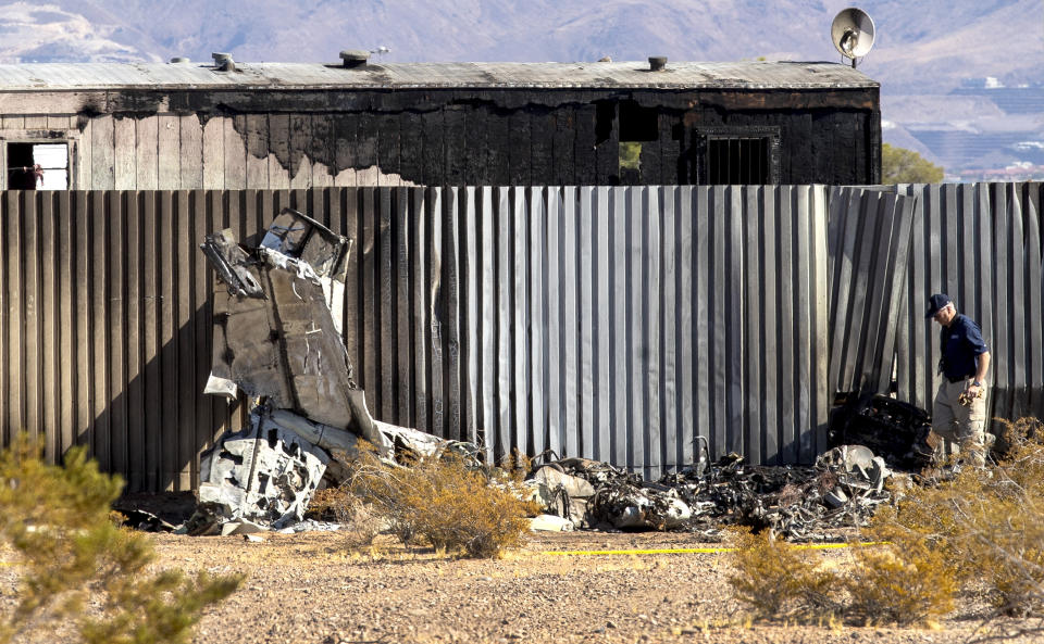 An investigator looks at the site of a deadly plane crash Thursday, Oct. 29, 2020, in Las Vegas. A twin-engine aircraft crashed shortly after takeoff Thursday, killing two people and igniting a fire that damaged a construction trailer from which a man escaped while choking on fuel fumes. (Steve Marcus/Las Vegas Sun via AP)